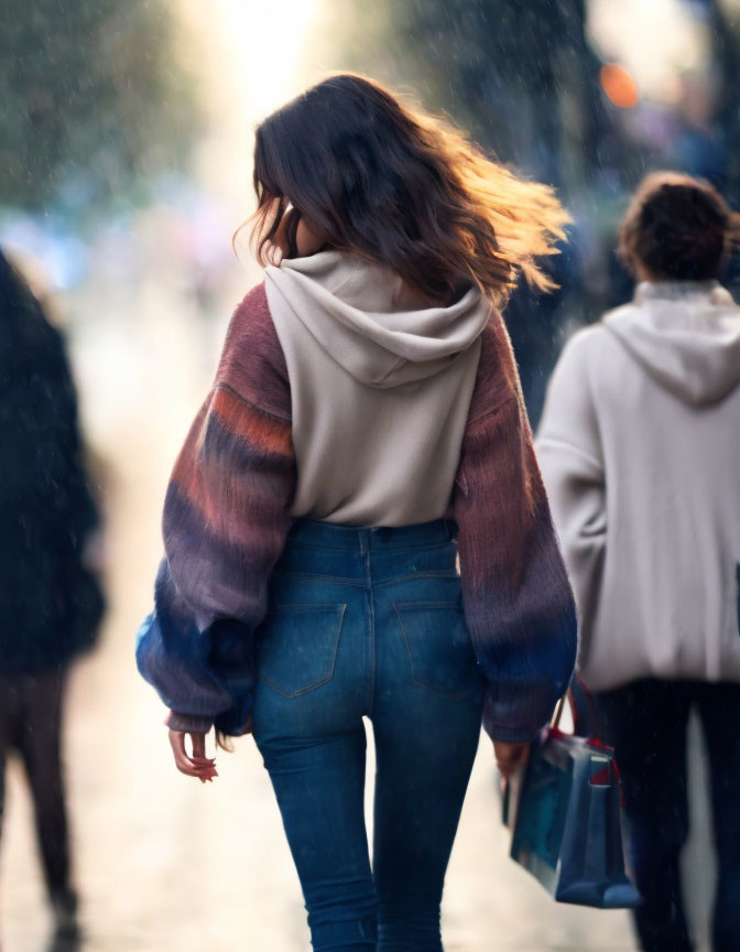 Woman in gradient sweater walking on busy street with tousled hair