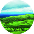 Circular image of colorful snowmen on green hill with misty blue mountains