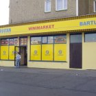 Yellow Industrial Building with Garage Doors and Gear Graphics Against Cliff Backdrop