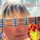 Woman with Bangs Holding Gemstone Sunglasses in Colorful Sunlit Scene