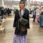 Woman in Black Coat and Hat on Flower-Strewn Street with Vintage Cars and Snowflakes