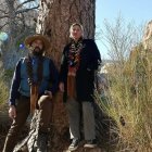 Men in traditional Western attire in desert landscape with cacti.