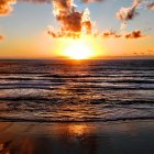 Colorful sunset painting with orange clouds and ocean reflections