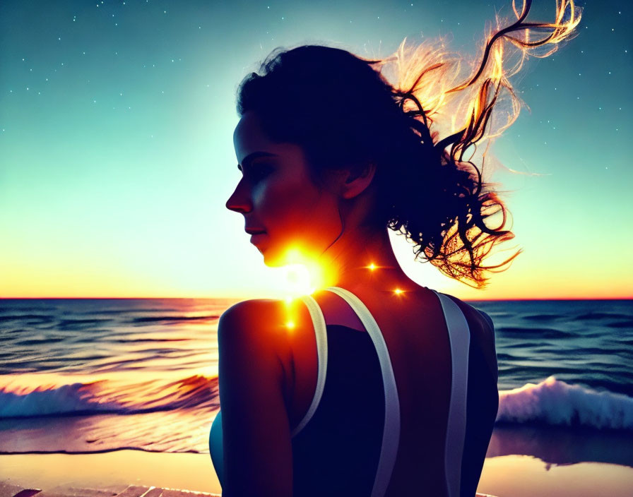 Silhouette of woman with flowing hair at sunset by ocean