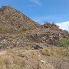 Red rock formations and SUVs on dusty trail under blue sky