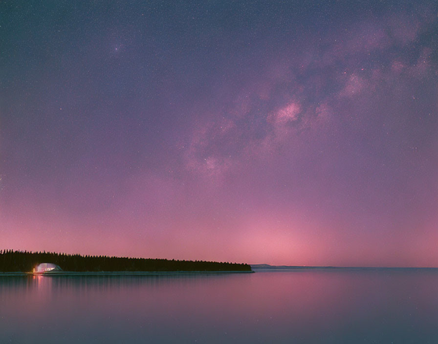 Starry Milky Way over tranquil nightscape with water and trees