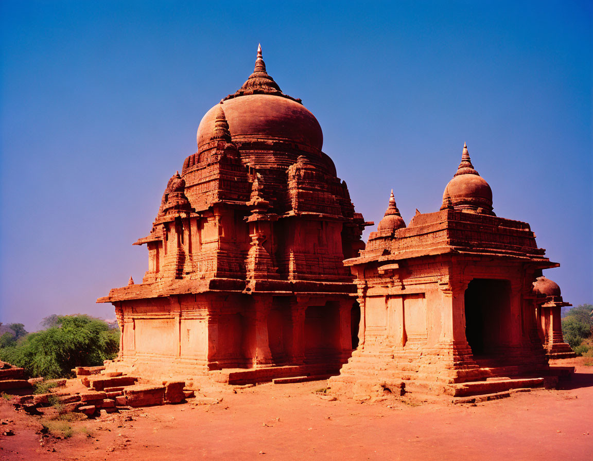 Ancient red sandstone temples with domes under clear blue sky