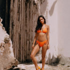 Woman in Orange Bikini Poses by Ancient Ruins on Sunny Day