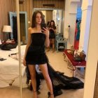 Person in elegant black dress takes selfie in lavish room.