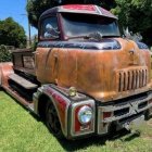 Faded vintage trucks in grassy field under clear sky