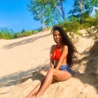 Woman in Red and Blue Swimsuit on Sandy Beach with Sea View