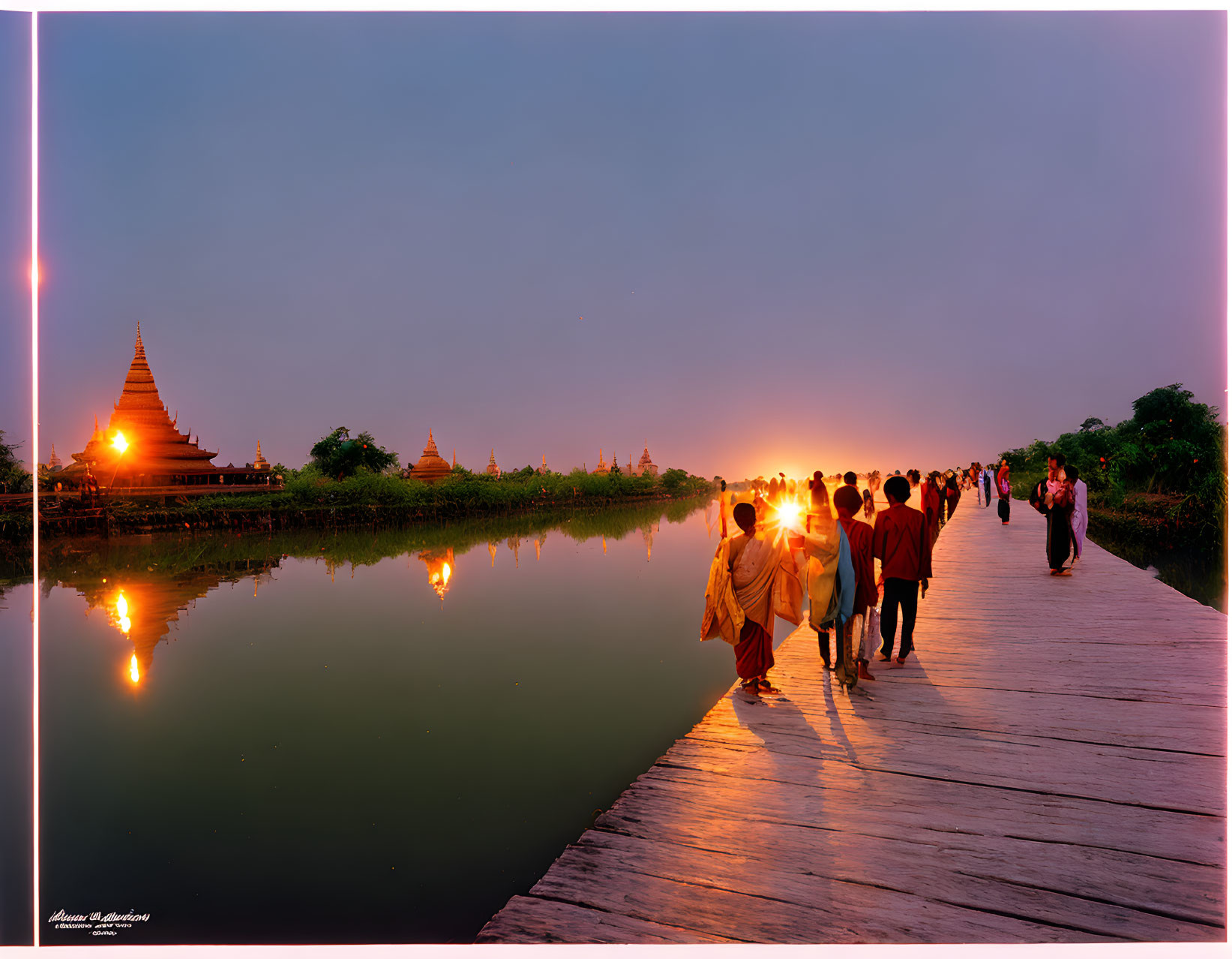 Twilight scene: People on wooden bridge with pagoda reflection