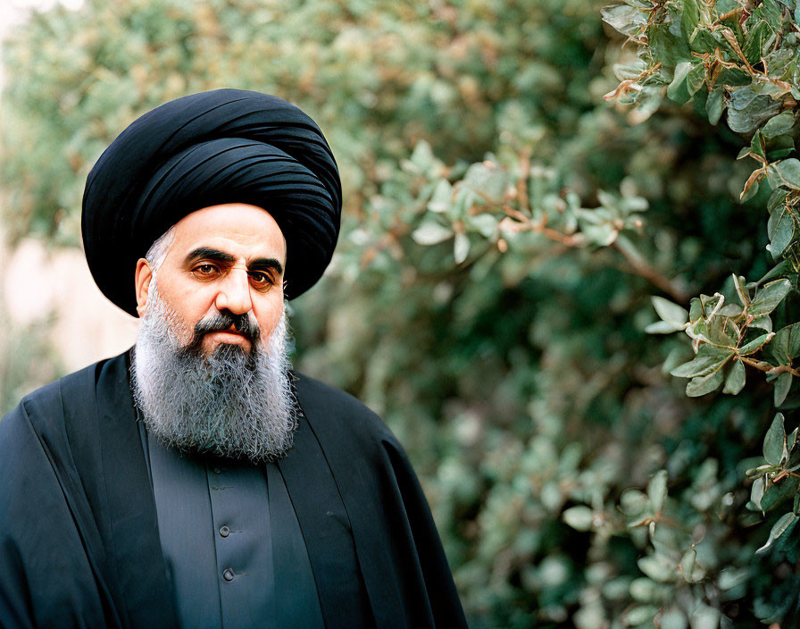 Man in Black Turban and Beard Contemplates in Front of Green Foliage