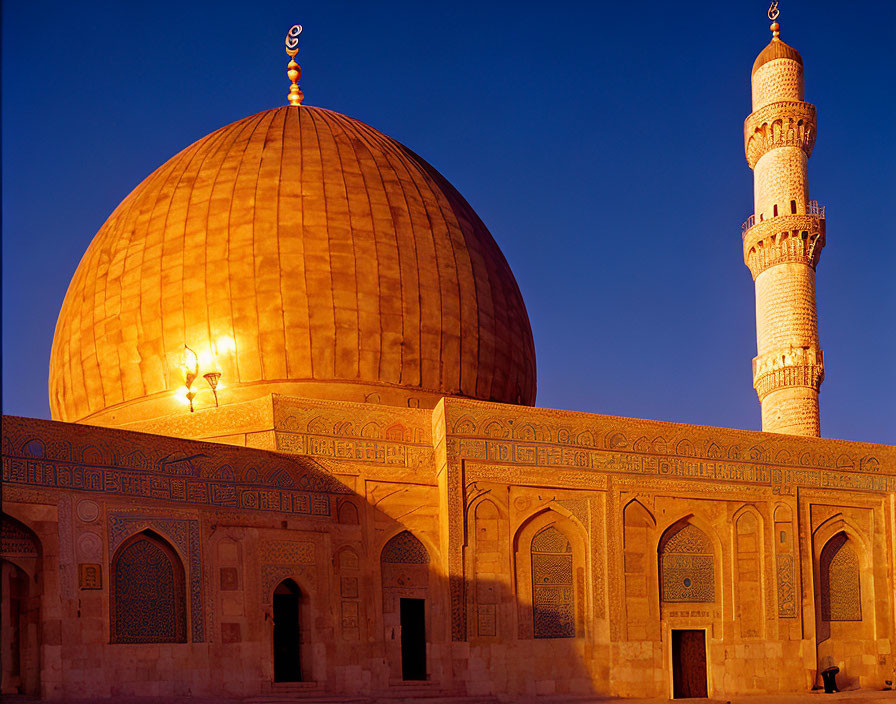 Intricate golden mosque dome at sunset with minaret against blue sky