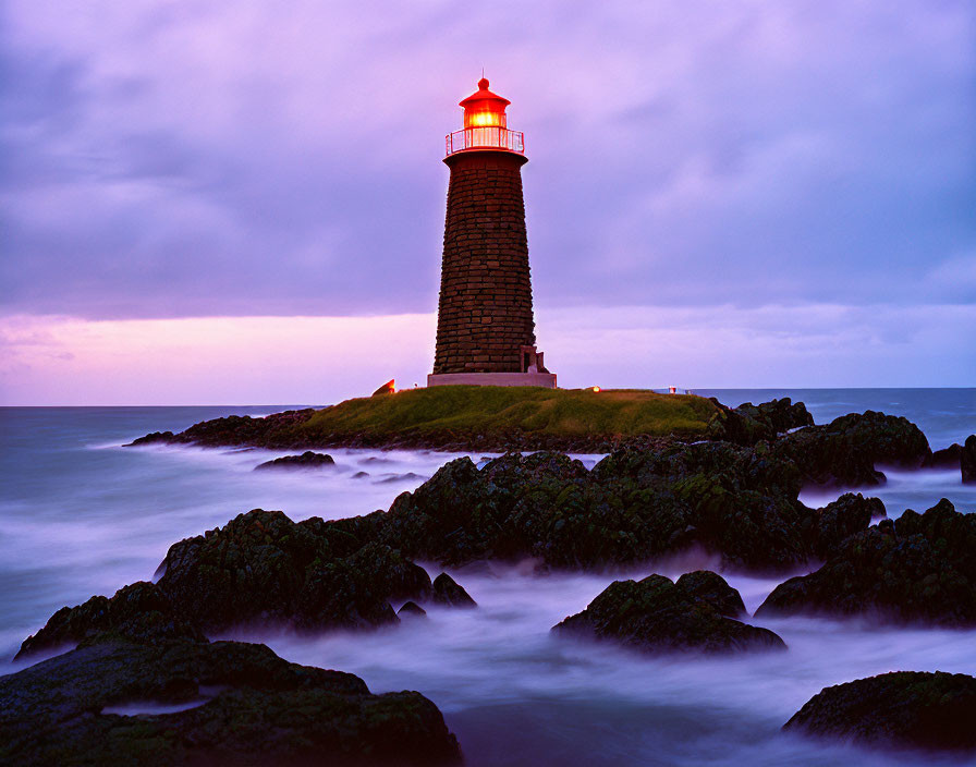 Lighthouse glowing in serene twilight on misty islet