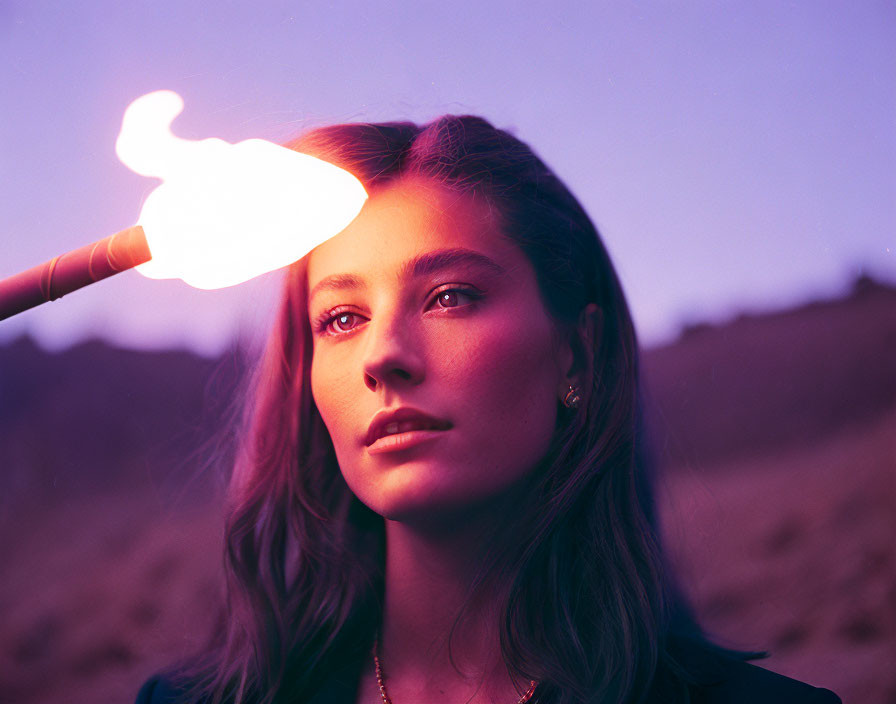 Serene woman standing in twilight with bright flame above her head