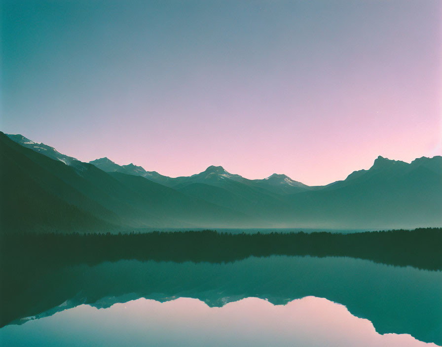 Serene lake at dawn with mountain reflections and gradient sky