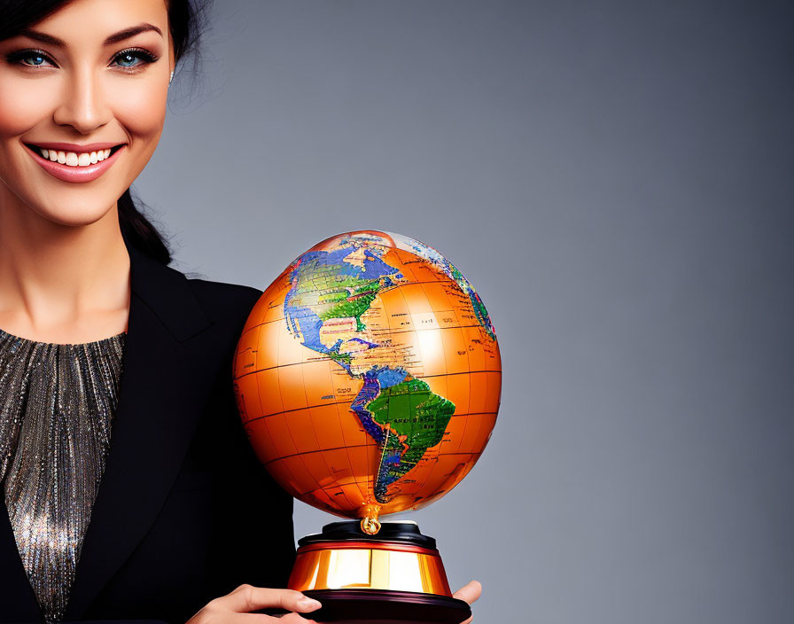 Smiling woman in black blazer with globe trophy on gray backdrop