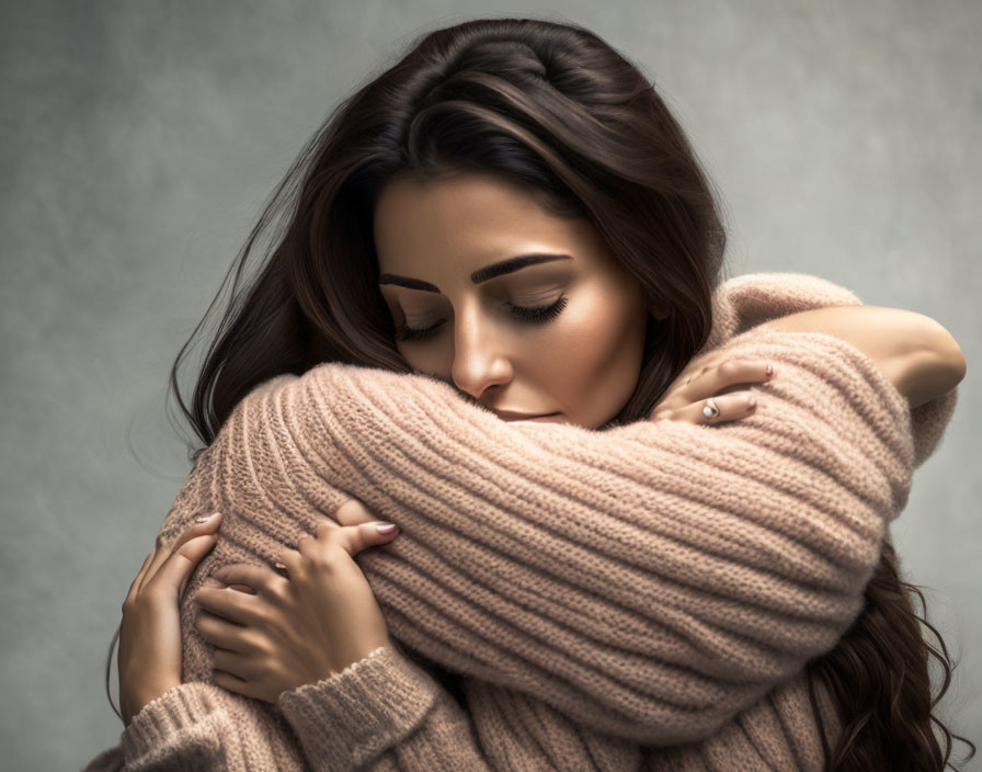 Woman in Pink Sweater Embracing Herself with Eyes Closed