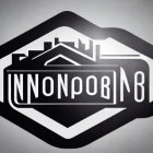 Hexagon-shaped Black and White Badge with Cyrillic Text and Industrial Skyline Silhouette