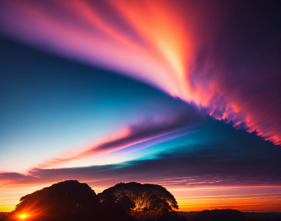 Colorful sunset sky above silhouetted trees: pink and blue streaks.