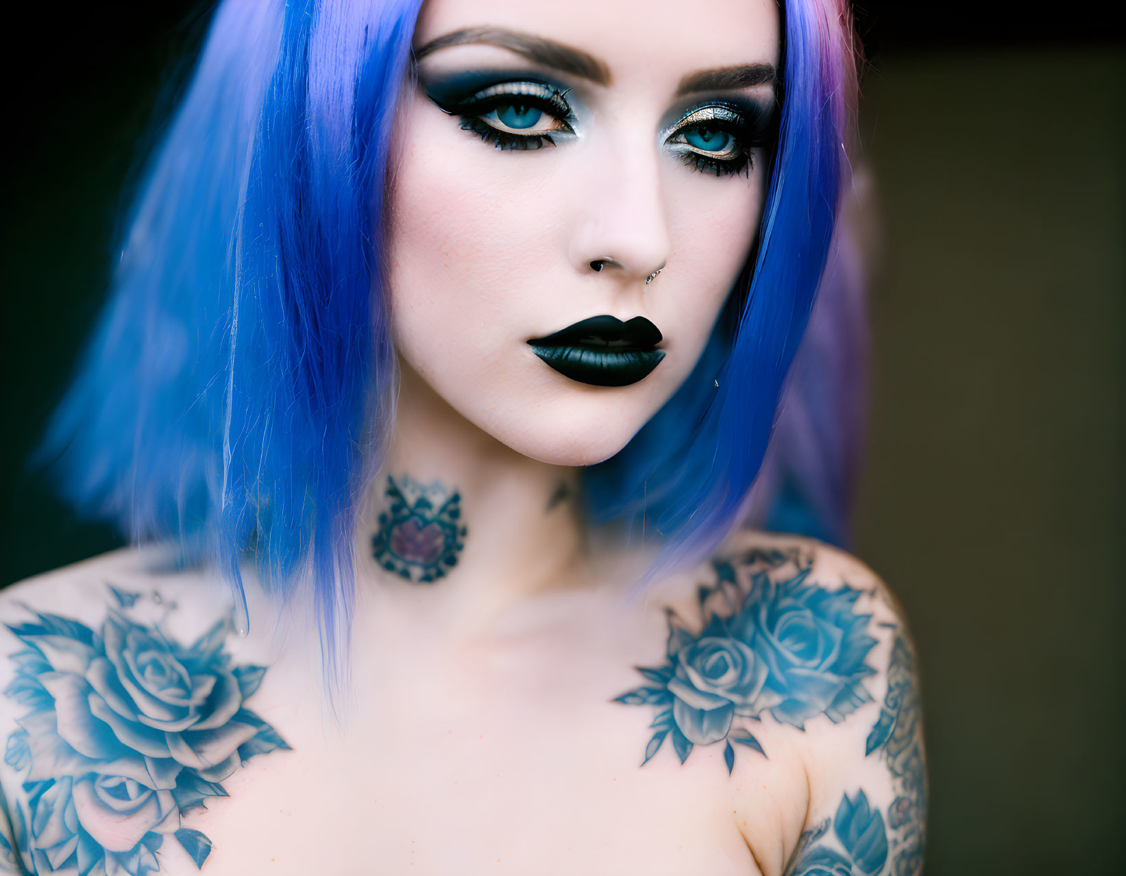 Vibrant blue hair, winged eyeliner, nose piercing, rose tattoos - woman's unique