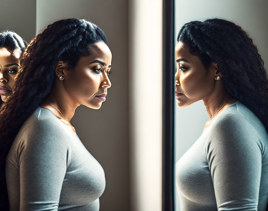 Braided hair woman gazes at reflection in mirror