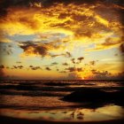 Vibrant sunset over calm ocean waters with orange and yellow skies.