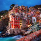 Coastal village at twilight with illuminated buildings above serene sea