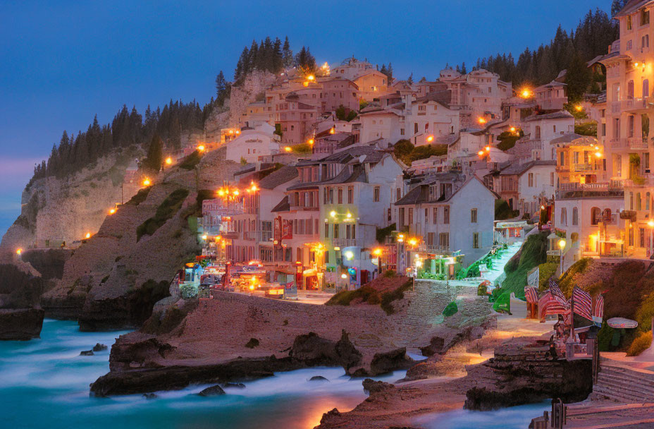 Coastal village at twilight with illuminated buildings above serene sea