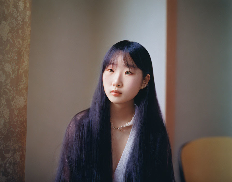 Young woman with long dark hair in vintage-style room setting.