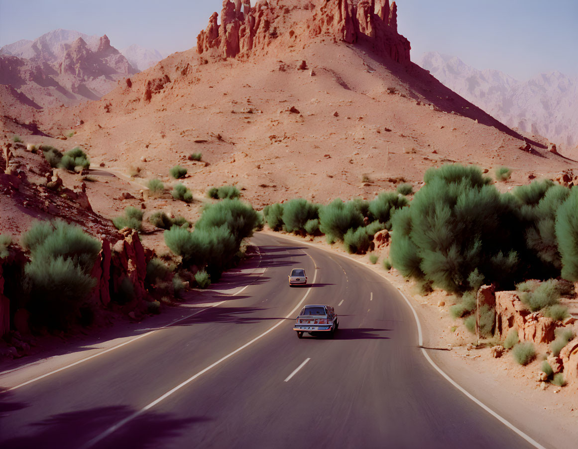 Desert landscape with winding road and two vehicles.