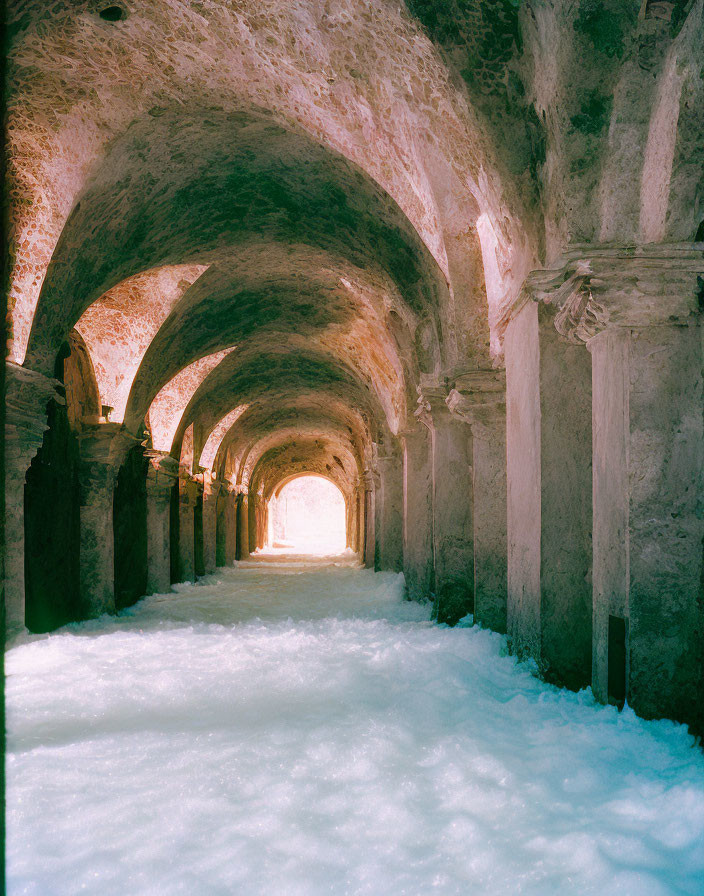 Snow-filled corridor with sequential arches creates serene indoor winter scene