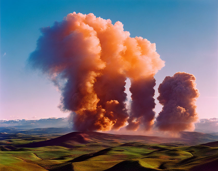 Vibrant green hills and billowing orange smoke plumes on blue sky