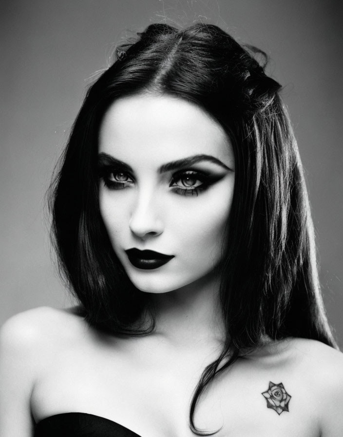 Monochrome portrait of a woman with dark lipstick and collarbone tattoo.