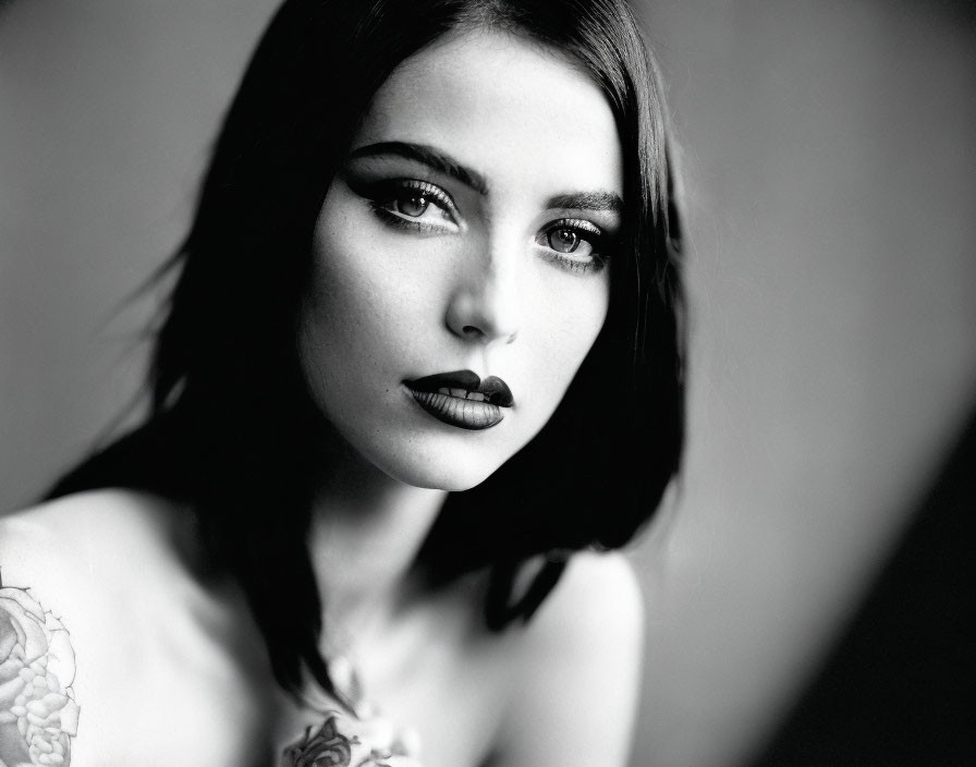 Monochrome portrait of woman with dark makeup and shoulder tattoo