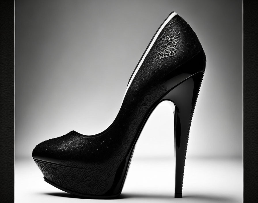 Black high-heeled shoe with intricate patterns on gray background