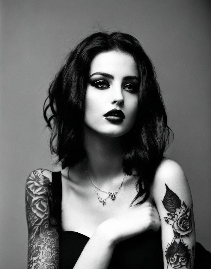 Monochrome portrait of woman with dark hair, lipstick, necklace, and floral tattoos