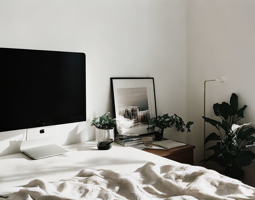 Minimalist Room with Black Desktop Computer, Artwork, Plants, and White Blanket