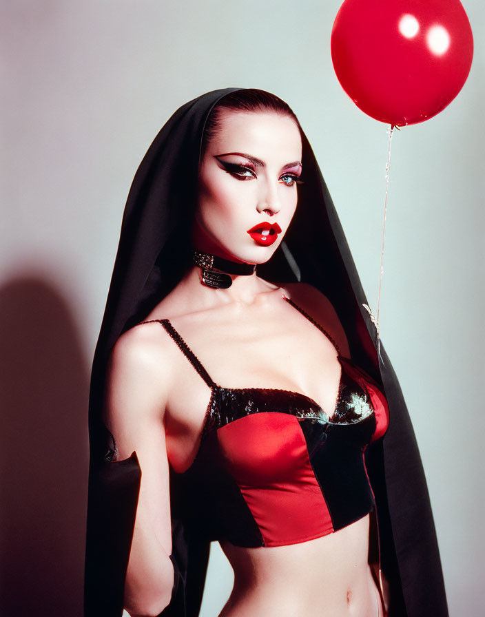 Woman in Red Bustier and Black Cloak with Red Balloon and Bold Makeup