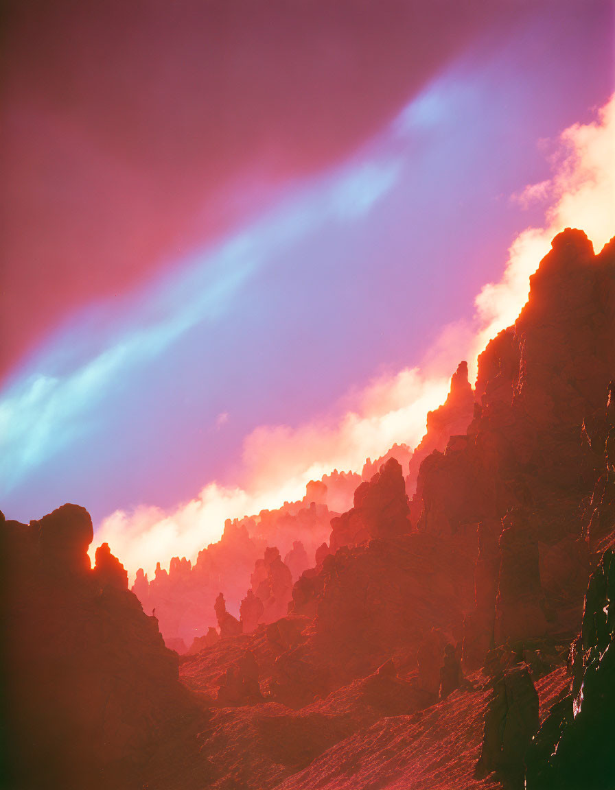 Vibrant sunset colors on rocky formations with piercing light beams.