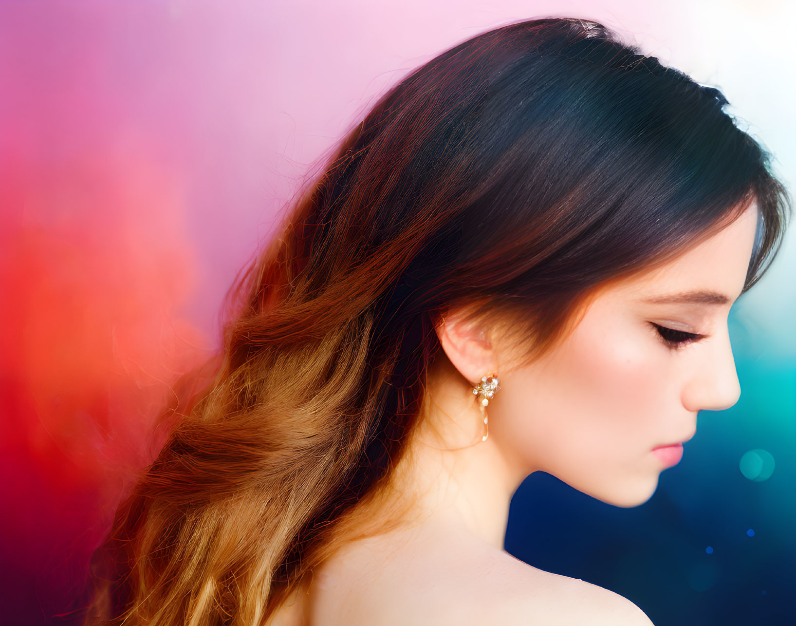 Young woman with dark hair and earring on vibrant pink and blue backdrop