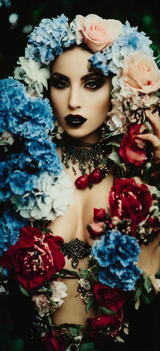 Woman with dramatic makeup among vibrant flowers: blue hydrangeas and pink roses