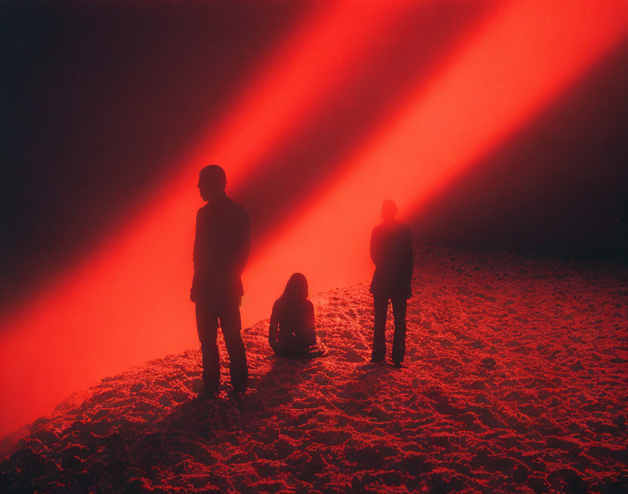 Silhouetted Figures Under Red Light Beams in Dusky Environment