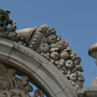 Detailed Stone Arch Carvings of Fruits, Leaves, and Bird on Sky Background