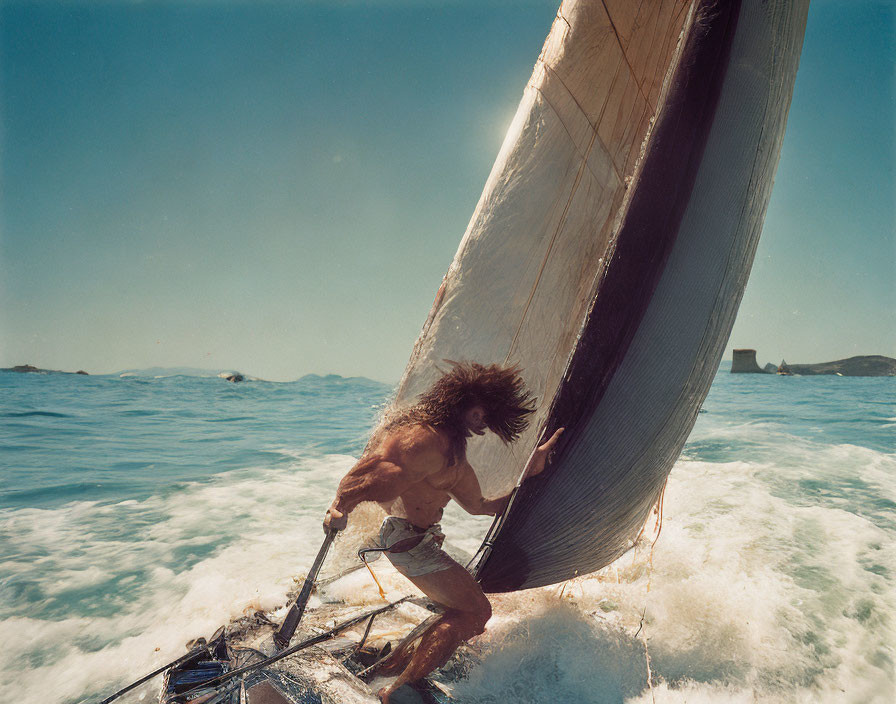 Shirtless man balancing on catamaran sail in choppy waves