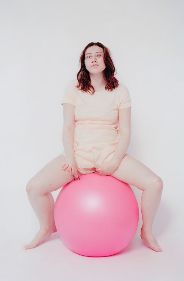 Brown-Haired Person on Pink Exercise Ball in Peach Outfit