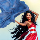 Woman in flowing red dress with blue scarf smiling against blurred background