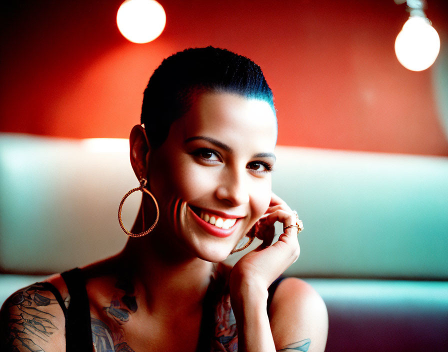 Smiling woman with short hair and tattoo sleeves in diner booth