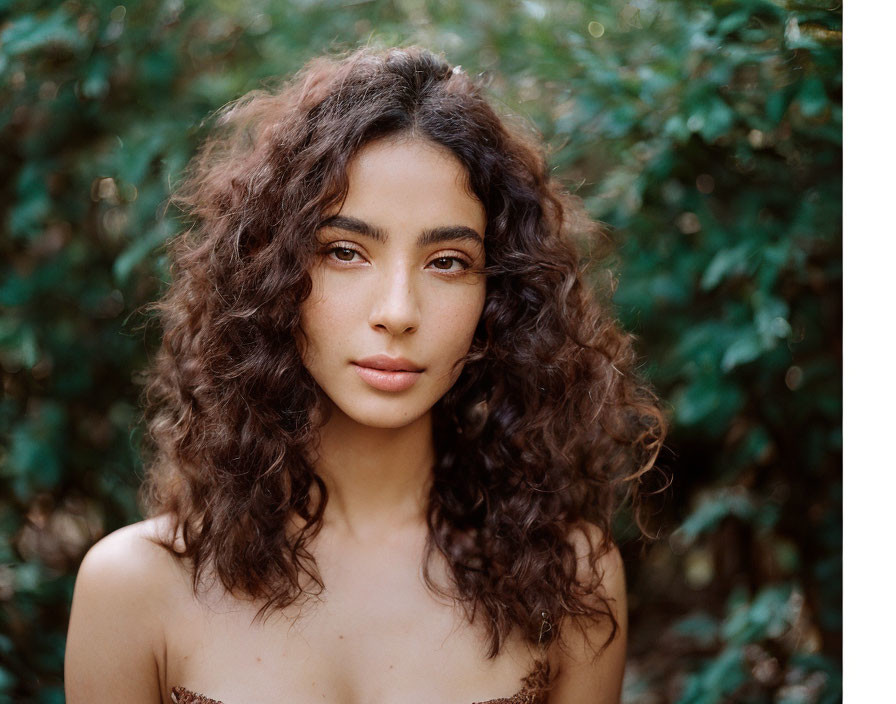 Curly Haired Woman Serenely Posed in Leafy Setting